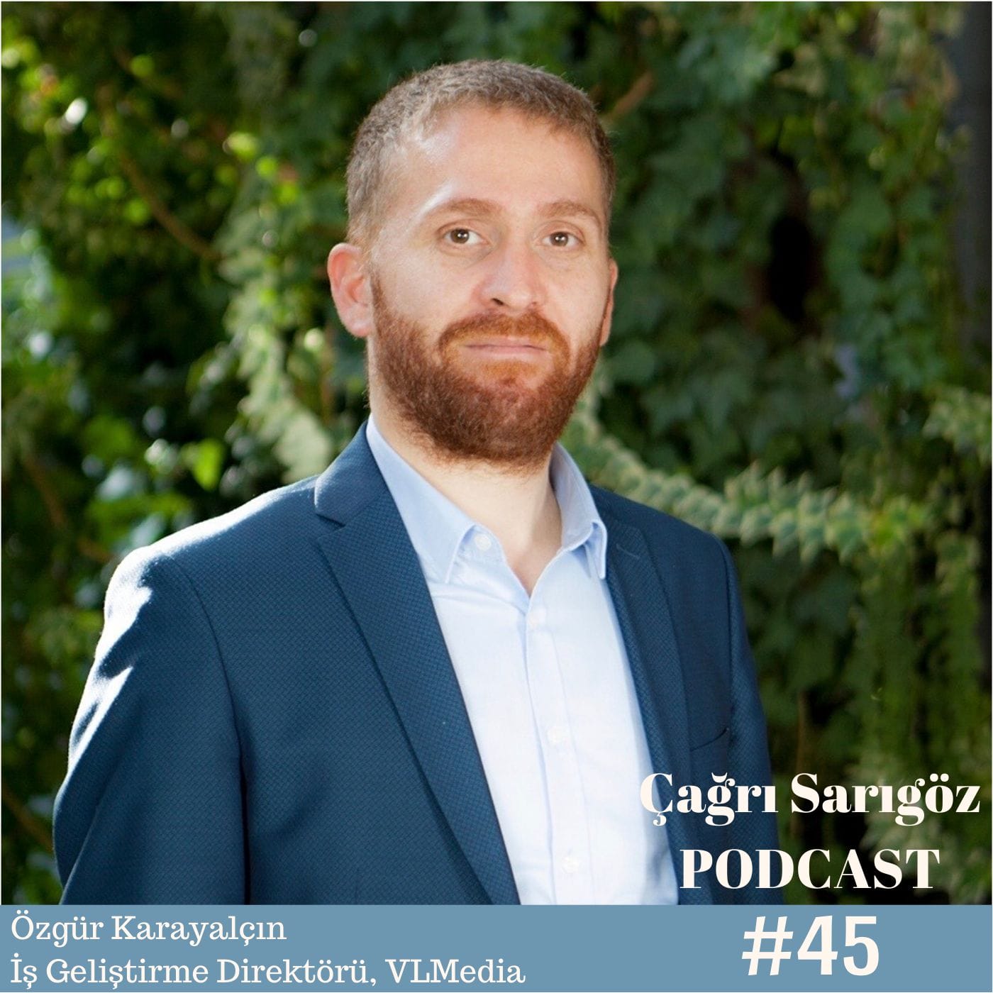 A man in a suit is standing in front of a tree.